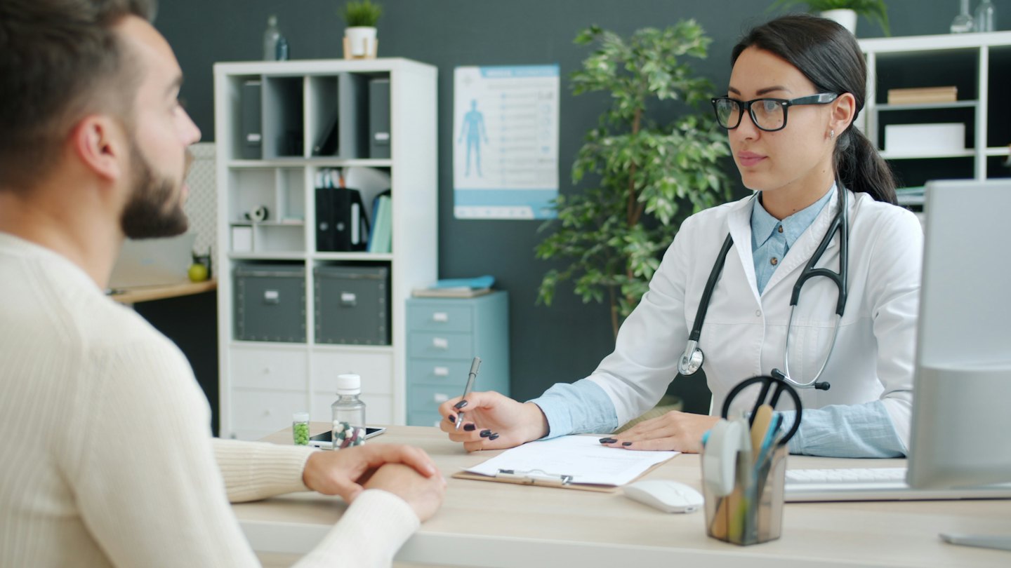 Arzt mit Stift berät Patient in Praxis.